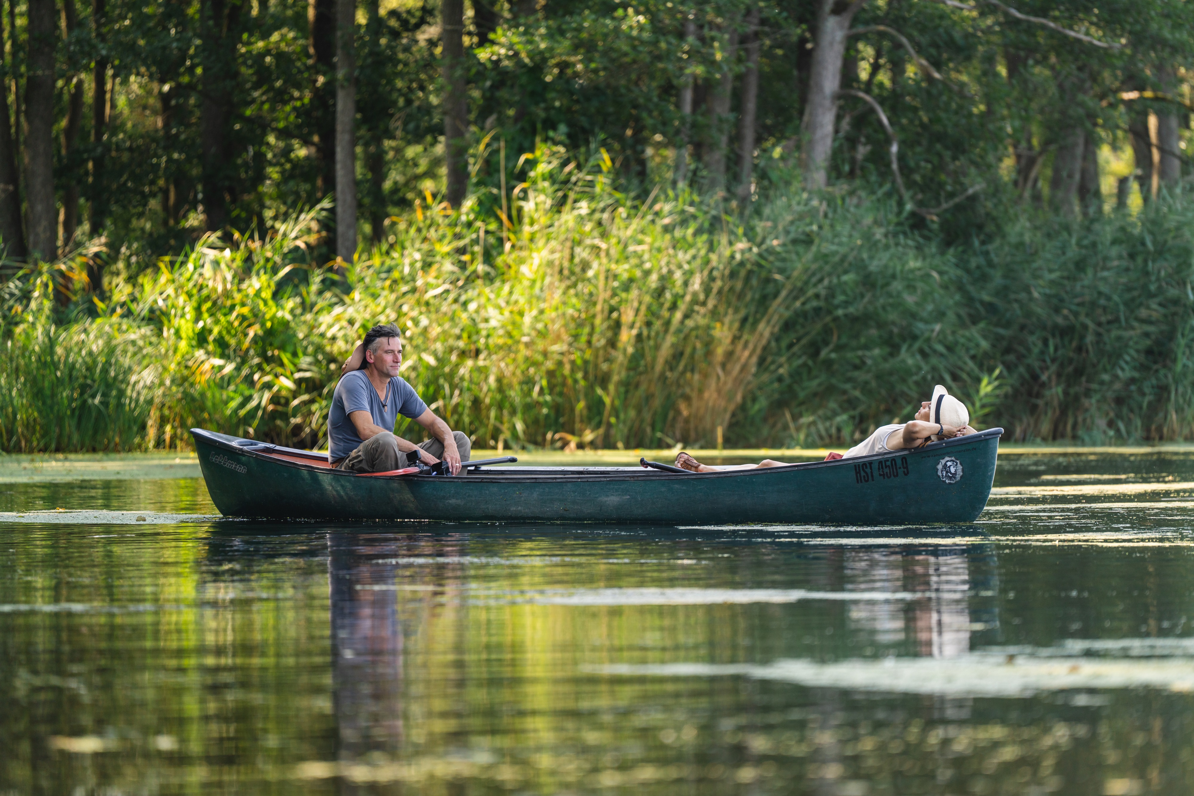 Zwei Personen lassen sich in einem Paddelboot auf der Peene treiben.